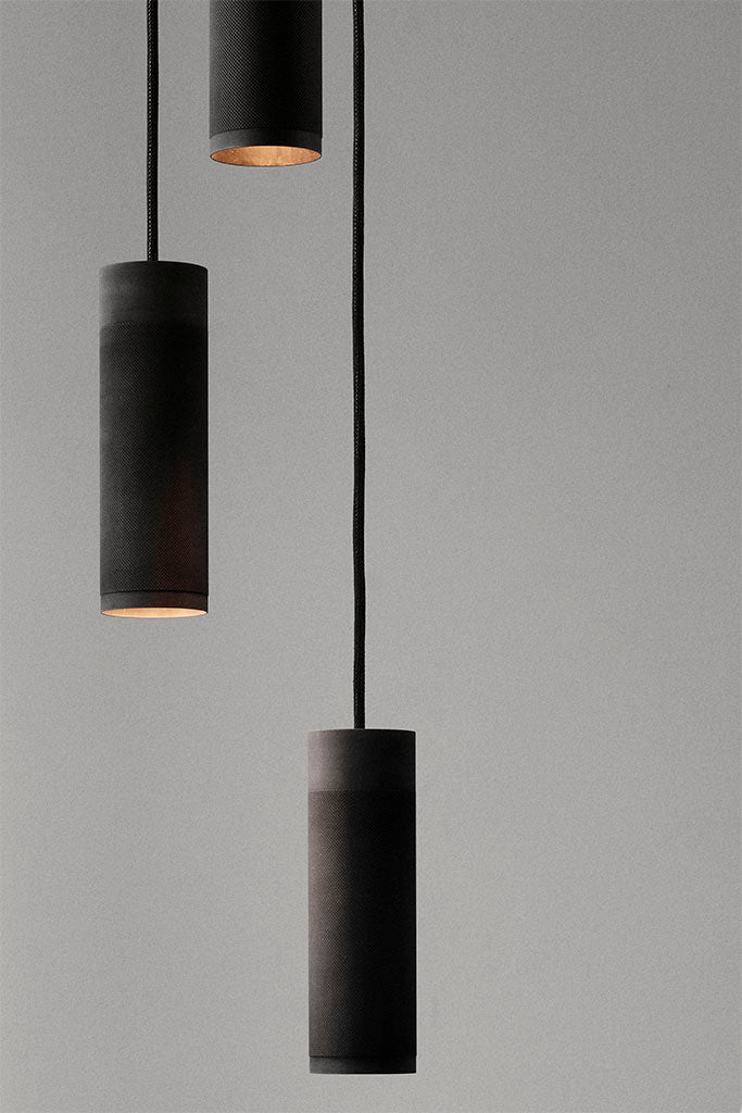 Nærbillede af loftlampe med tre pendler i massiv sort bruneret messing med sort stofledning