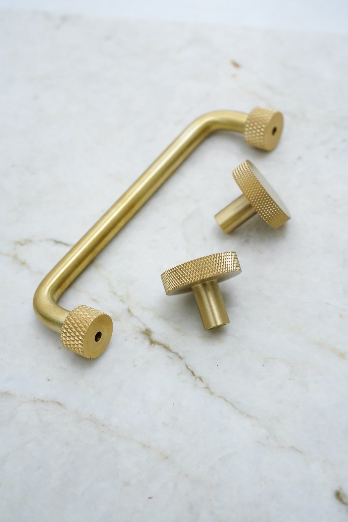 Kitchen handle in solid brass without lacquer. The handle has round feet with a knurled diamond-cut pattern that matches Quooker taps.